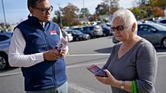 Republican candidate for New York's 3rd Congressional District George Santos, left, talks to a voter while campaigning outside a Stop and Shop store, 5 November 2022
