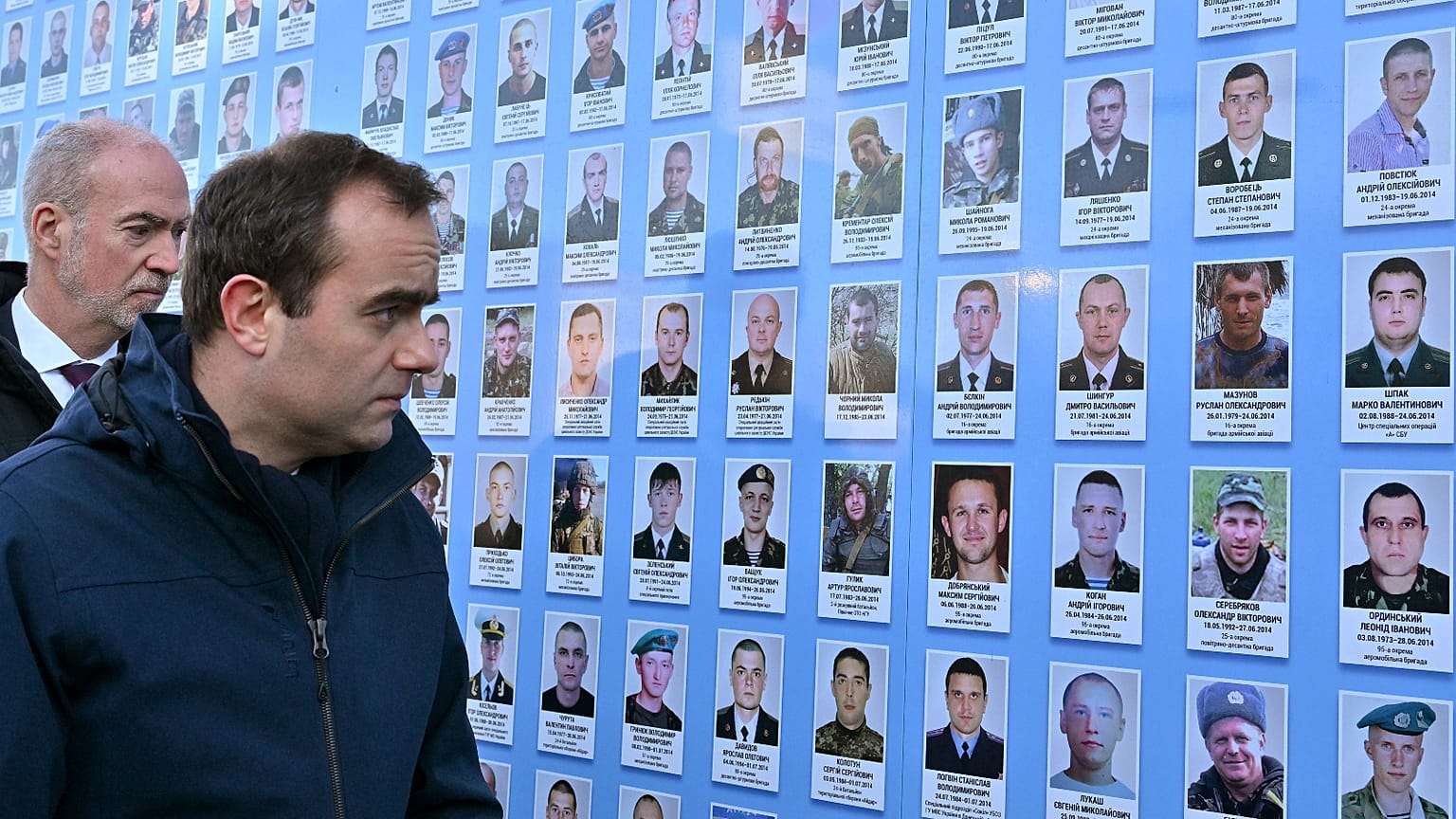 French Armies Minister Sebastien Lecornu (L) and French Ambassador to Ukraine Etienne de Poncins (R) stand in front of the Memorial Wall of Fallen Defenders of Ukraine in Kyiv