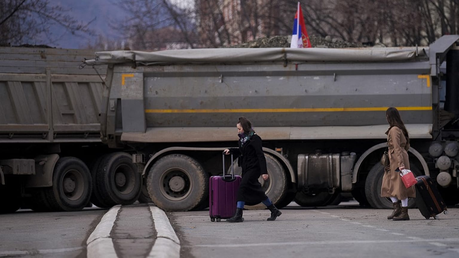 Pedestrians walk past a new road barricade set up in the divided town of Mitrovica on December 28, 2022. 