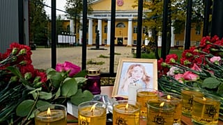 Flowers, candles and a portrait of one of victims are displayed on a table outside the Perm State University.