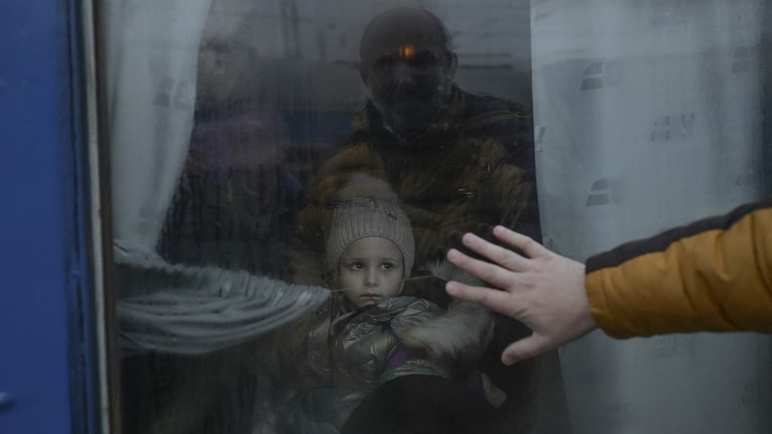 A father puts his hand on the window as he says goodbye to his daughter in front of an evacuation train at the central train station in Odessa on March 7, 2022.