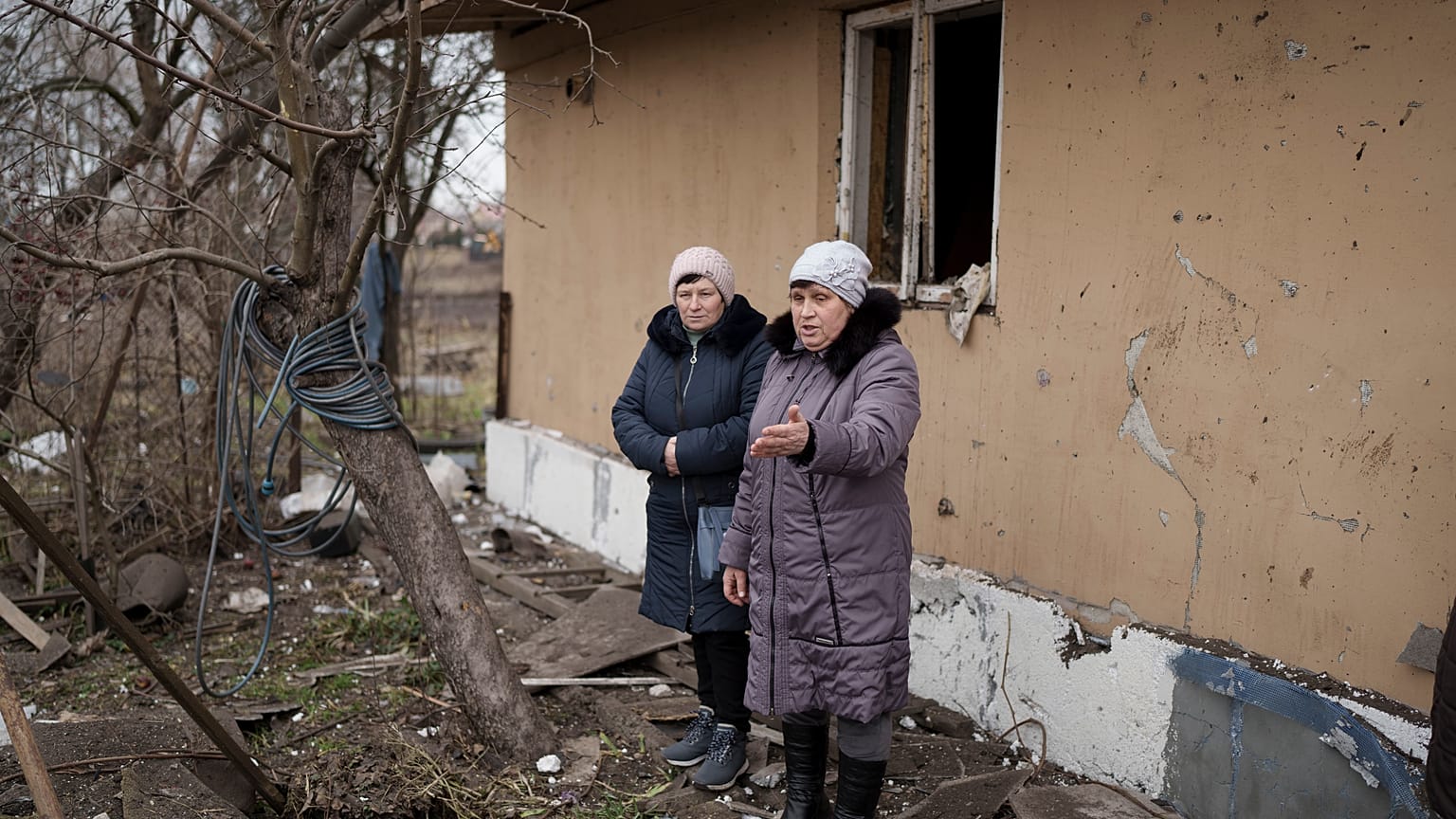 Local residents stand among debris after residential houses were damaged following a Russian missile attack in Kyiv.