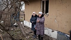 Local residents stand among debris after residential houses were damaged following a Russian missile attack in Kyiv.