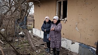Local residents stand among debris after residential houses were damaged following a Russian missile attack in Kyiv.