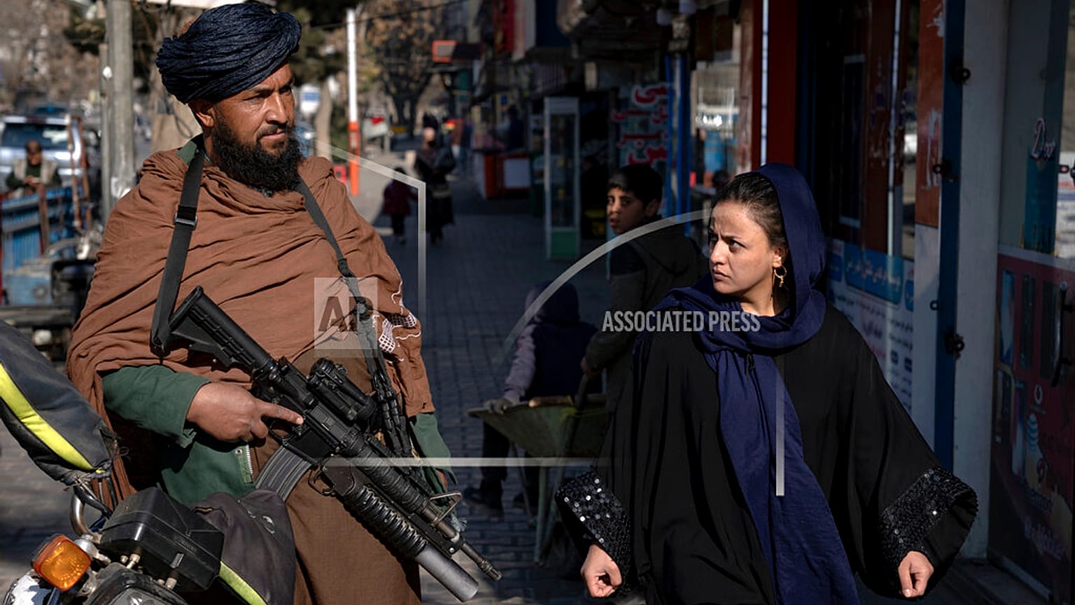 Un talebano controlla la strada mentre una donna passa a Kabul, in Afghanistan, il 26 dicembre 2022.