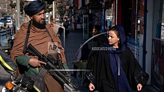 Un talebano controlla la strada mentre una donna passa a Kabul, in Afghanistan, il 26 dicembre 2022.