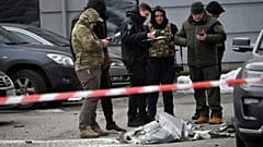 Police experts examine remains of a downed missile which fell on a vehicle parked at a multi storey residential building in Kyiv on December 29, 2022