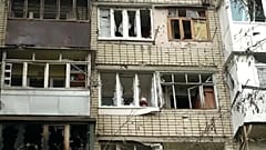 Un habitant à sa fenêtre détruite par un bombardement dans le quartier de Korabel, de la ville de Kherson, en Ukraine le 29 décembre 2022.
