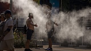 Archives : personnes se rafraichissant grâce à des brumisateurs installés dans les rue de Barcelone en proie à une canicule, le 16 juillet 2022