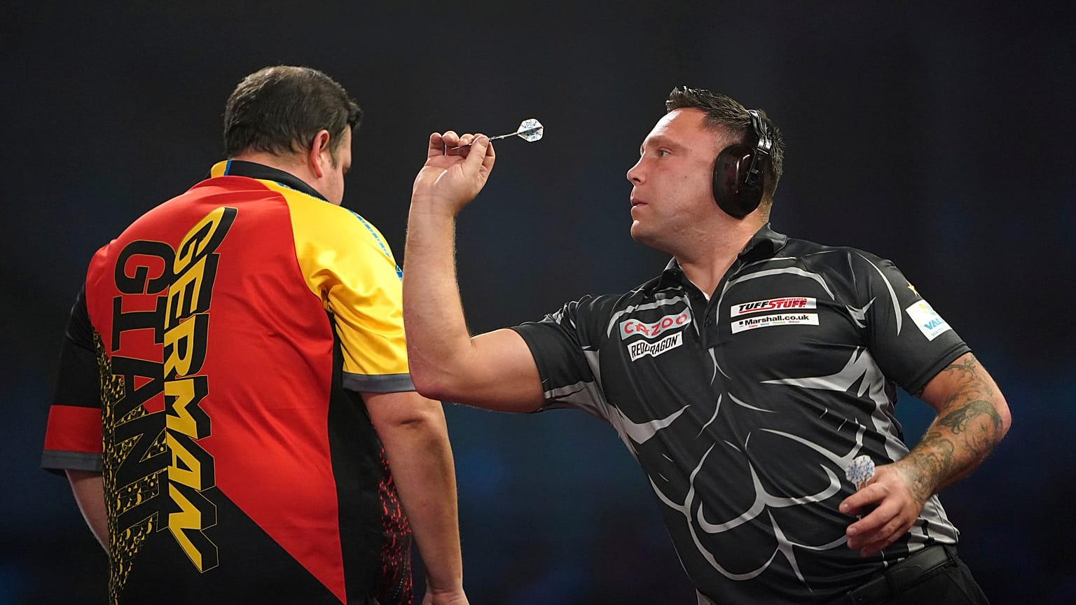 Gerwyn Price wears ear defenders as he plays against Germany's Gabriel Clemens