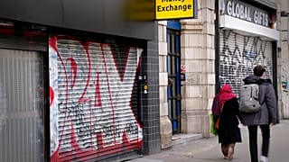 Pedestrians pass a closed down money exchange shop on Oxford Street in London, Friday, Nov. 11, 2022. 