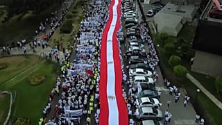 Cientos de personas llevan una bandera peruana en la manifestación por la paz en Lima este martes.