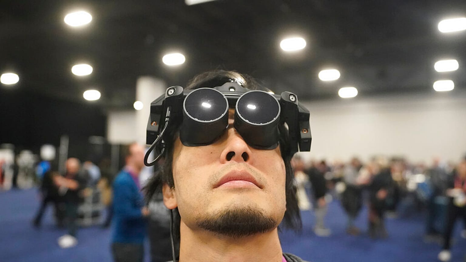 Un homme fait la démonstration du casque de réalité virtuelle Megane X, plus léger et compact que ses concurrents.