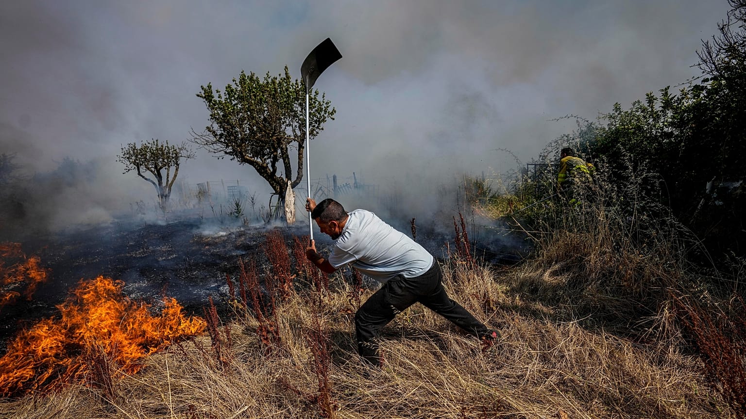 A local resident fights a forest fire with a shovel during a wildfire in Tabara, north-west Spain, Tuesday, July 19, 2022. 