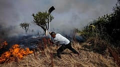 A local resident fights a forest fire with a shovel during a wildfire in Tabara, north-west Spain, Tuesday, July 19, 2022. 