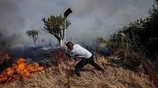 A local resident fights a forest fire with a shovel during a wildfire in Tabara, north-west Spain, Tuesday, July 19, 2022. 