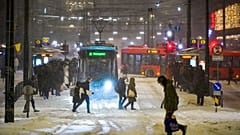 Straßenbahnen und Busse im Schneetreiben am Jernbanetorget im Zentrum von Oslo