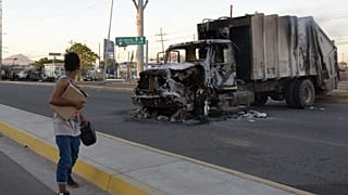 Une femme passe devant un camion incendié à Culiacan (Mexique).