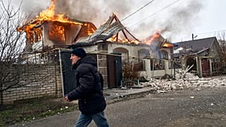 A local resident runs past a burning house hit by the Russian shelling in Kherson on 6 January 2023