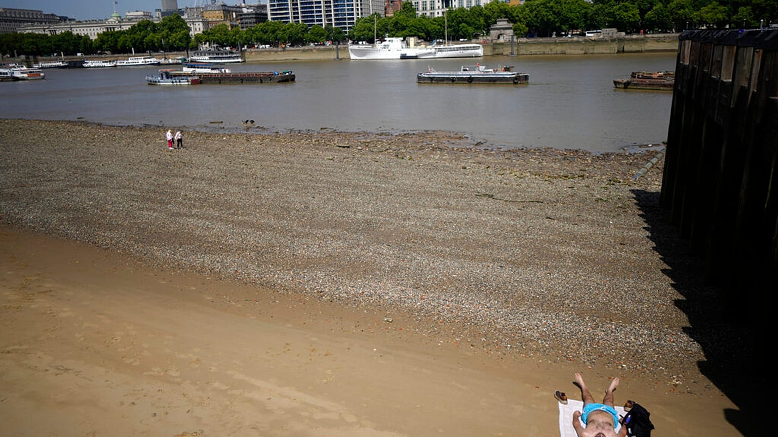 A man sun bathes on the beach on the bank of the River Thames in London, Friday, June 17, 2022.