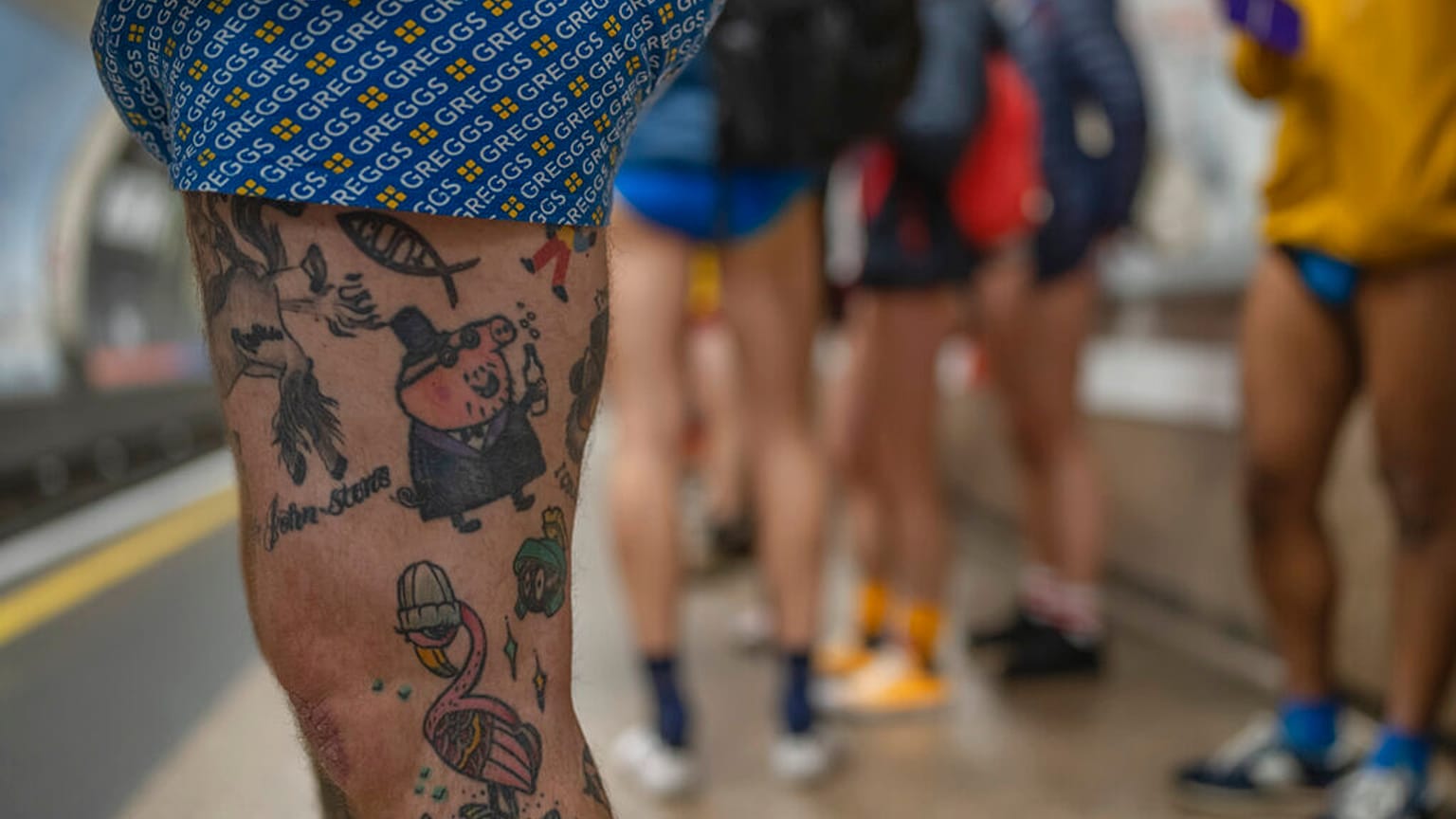 People wait for an underground train as they take part in the annual event "No Trousers Tube Ride" in London, Sunday, Jan. 8, 2023. 