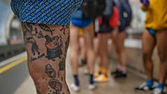 People wait for an underground train as they take part in the annual event "No Trousers Tube Ride" in London, Sunday, Jan. 8, 2023. 