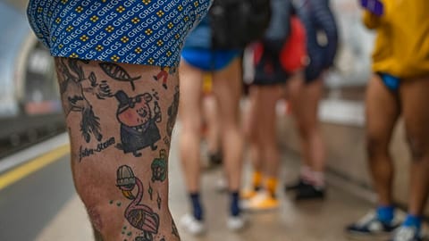 People wait for an underground train as they take part in the annual event "No Trousers Tube Ride" in London, Sunday, Jan. 8, 2023. 