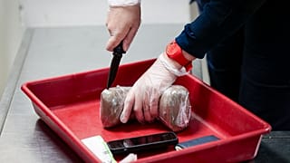 Полицейский открывает упаковку с конфискованным с парижском аэропорту кокаином. Архив