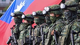 Soldiers pose for group photos with a Taiwan flag after a preparedness enhancement drill simulating the defense against Beijing's military intrusions.