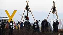 Police officers stand in front of a baricade of climate activists at the village Luetzerath near Erkelenz, Germany, Wednesday, Jan. 11, 2023.