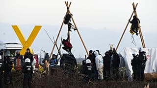 Police officers stand in front of a baricade of climate activists at the village Luetzerath near Erkelenz, Germany, Wednesday, Jan. 11, 2023.