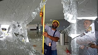 Des ouvriers mesurent les fenêtres brisées du palais de Planalto au lendemain de l'assaut des partisans de Jair Bolsonaro à Brasilia, lundi 9 janvier 2023.