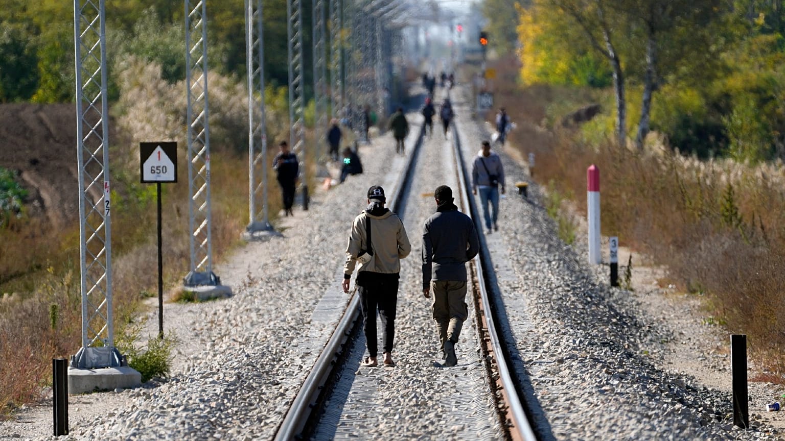Migrants walk on the railway tracks near a border line between Serbia and Hungary, near village of Horgos, Serbia, Oct. 20, 2022. 