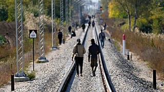 Migrants walk on the railway tracks near a border line between Serbia and Hungary, near village of Horgos, Serbia, Oct. 20, 2022. 