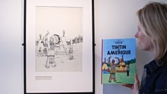 مديرة "آر كوريال" في بلجيكا  فينسيان دو ترو تقف أمام الرسم الأصلي لغلاف مجلّد قصة "تان تان في الولايات المتحدة" الذي أصدر عام 1942.