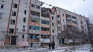 Residentes locales caminan frente a una casa destruida por los bombardeos rusos en Siversk, región de Donetsk, Ucrania.