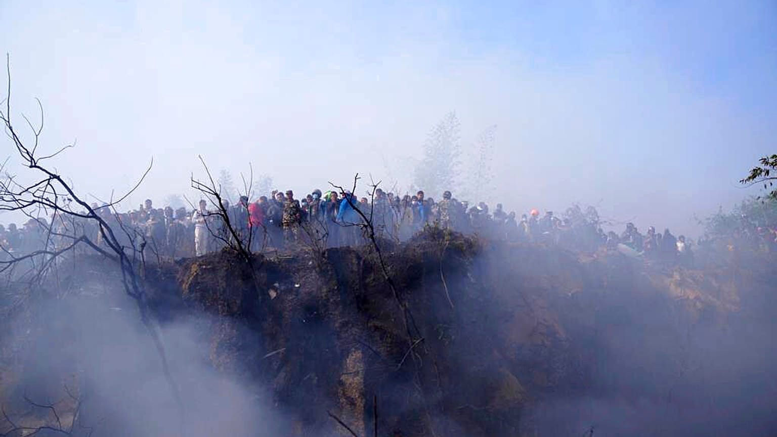 Locals watch the wreckage of a passenger plane in Pokhara, Nepal, Sunday, Jan.15, 2023. 