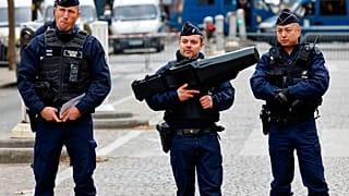 French police officers stand guard with an anti-drone gun, centre, during ceremonies Friday Nov.11, 2022.