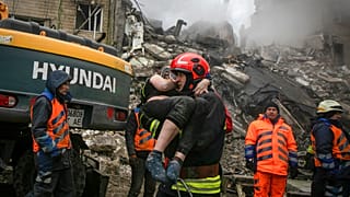 Emergency workers carry a wounded woman after a Russian rocket hit a multistory building on Saturday in Dnipro, Ukraine, Sunday, Jan. 15, 2023. 