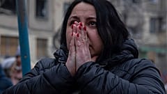 Schockiert schaut eine Frau in Dnipro auf die Trümmer eines Wohnhauses, in dem 1.700 Menschen lebten, und das von einer russischen Rakete getroffen wurde.