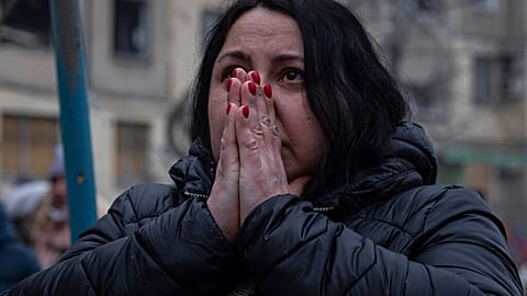 Schockiert schaut eine Frau in Dnipro auf die Trümmer eines Wohnhauses, in dem 1.700 Menschen lebten, und das von einer russischen Rakete getroffen wurde.