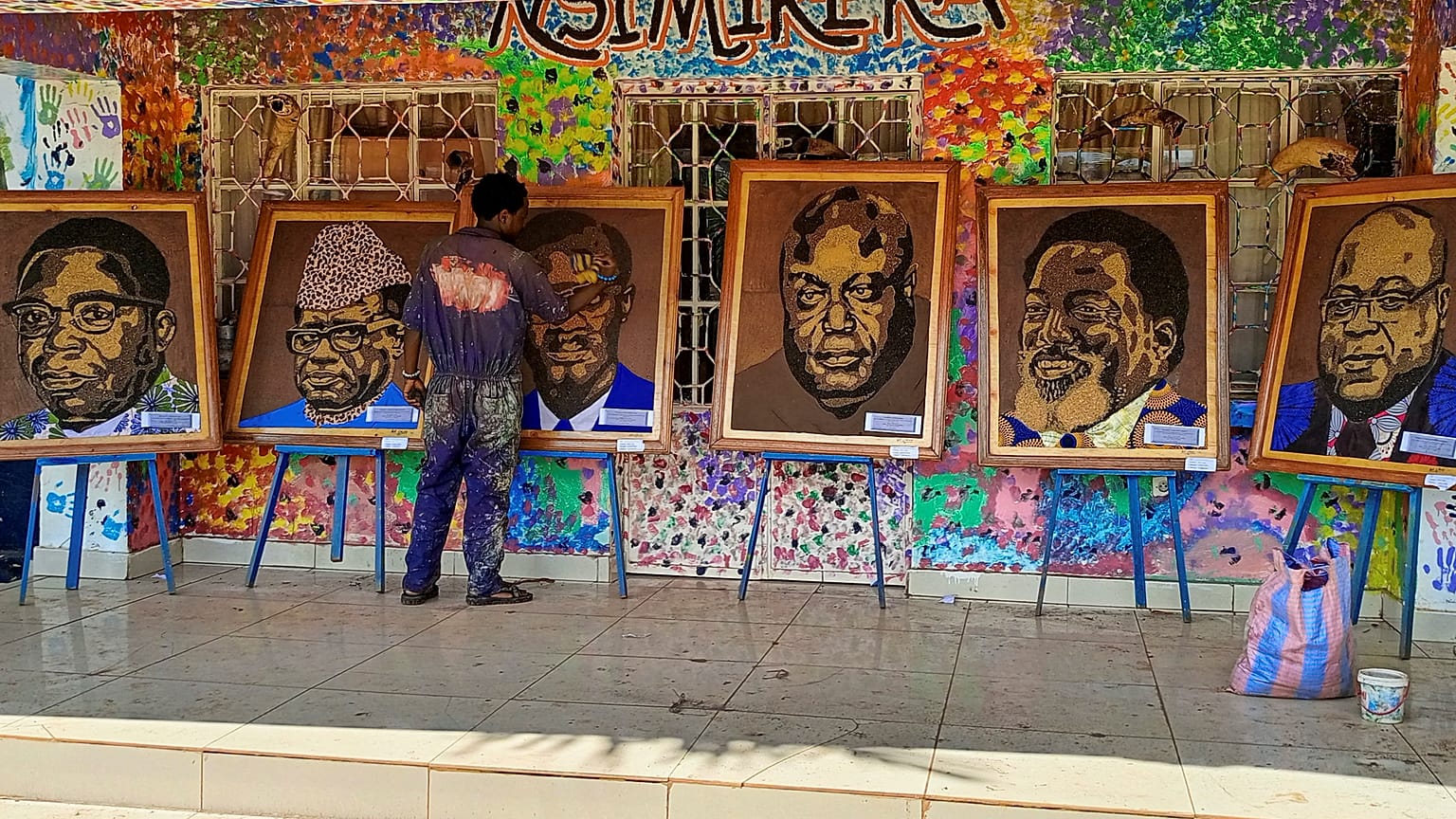 Patrick Cikuru Cirimwami with a collection of his portraits of D.R.C. politicians.