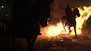 Un caballo pasa sobre una hoguera durante la celebración de Las Luminarias, en San Bartolomé de Pinares, Ávila, España.