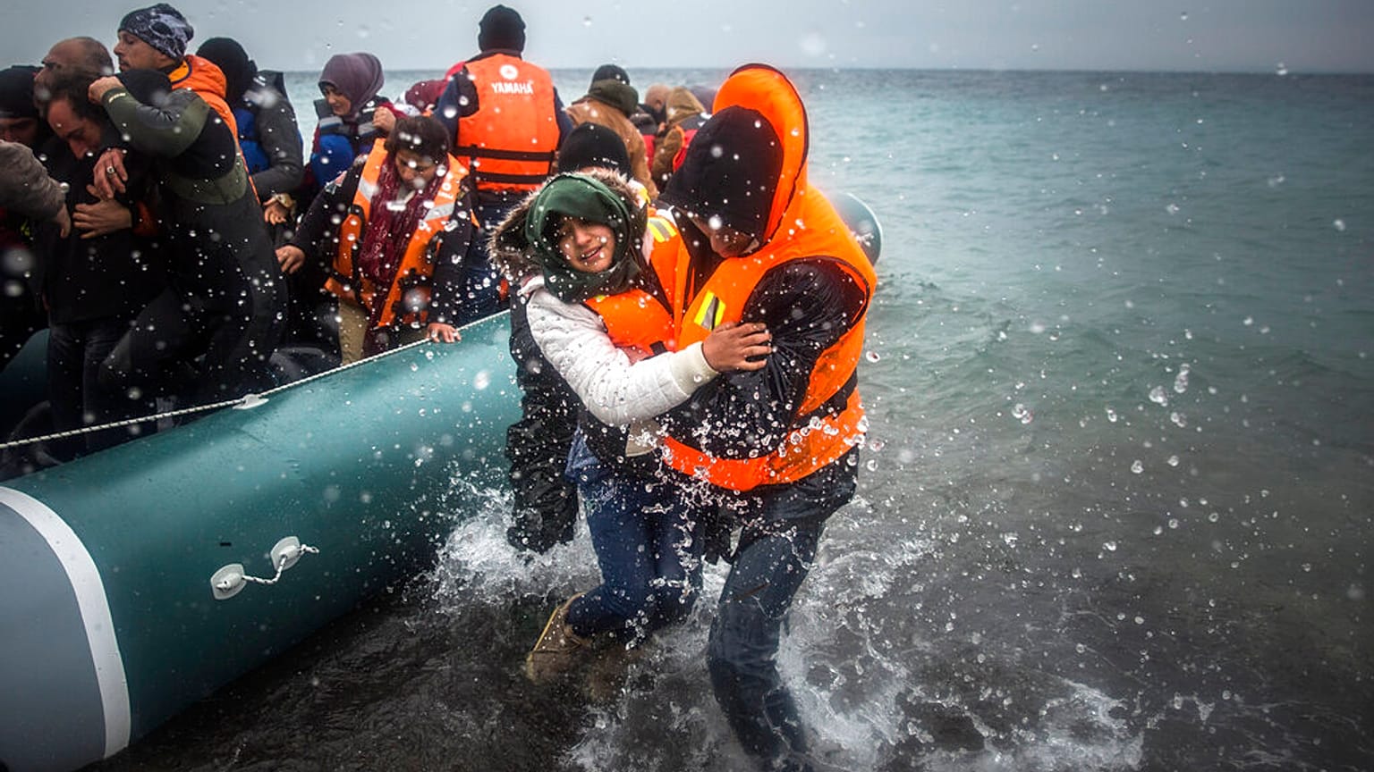 Jan. 3, 2016 file photo, refugees and migrants disembark on a beach after crossing a part of the Aegean sea from Turkey.