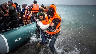 Jan. 3, 2016 file photo, refugees and migrants disembark on a beach after crossing a part of the Aegean sea from Turkey.