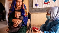 Σύμβουλος διατροφής της Save the Children εξηγεί σε μητέρα πώς να ταΐσει την 11 μηνών κόρη της με θεραπευτική τροφή, κατά του σοβαρού οξέος υποσιτισμού,