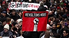 Manifestantes sostienen una pancarta con un puño y el texto en francés 'Levántate contra' en París, Francia, en 2019