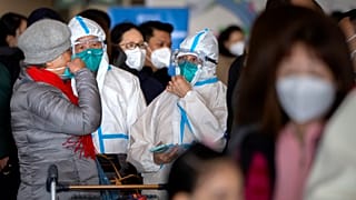 Travellers stand in line to check in for a Cathay Pacific flight to Hong Kong at Beijing Capital International Airport, 15 January 2023