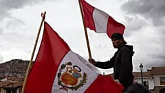 A person waves a Peruvian flag while waiting for other union groups to arrive at Plaza de Armas to join anti-government protests in Cusco, Peru