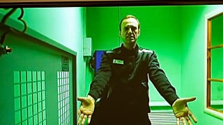 Russian opposition leader Alexei Navalny is seen on a TV screen, as he appears in a video link provided in a courtroom in Moscow, Russia, Tuesday, Oct. 18, 2022